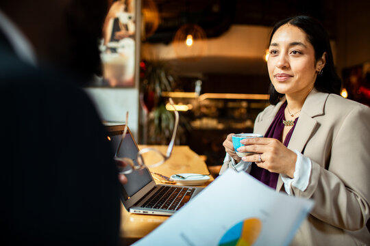 Businesswoman having coffee during meeting with colleague in cafe