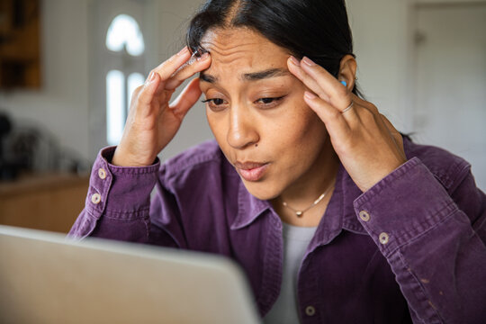 Stressed young woman working on laptop at home