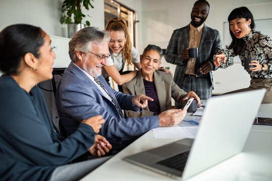 Diverse business team laughing during meeting in modern office