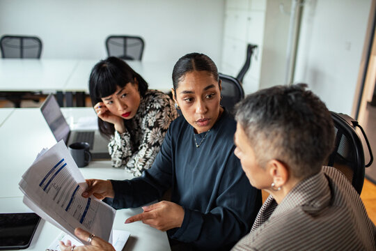 Three coworkers discussing financial report in modern office