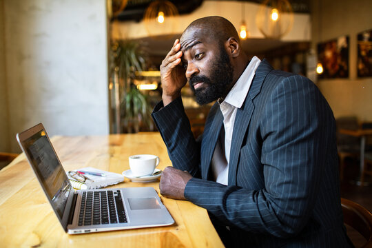 Businessman stressed while working on laptop in cafe