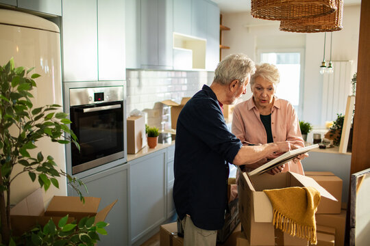 Senior couple unpacking moving boxes in kitchen