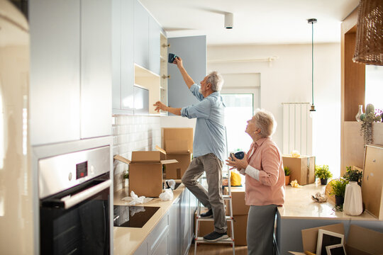 Senior couple unpacking and organizing dishes in new kitchen