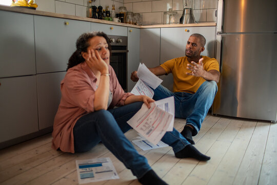 Stressed couple arguing over bills in home kitchen