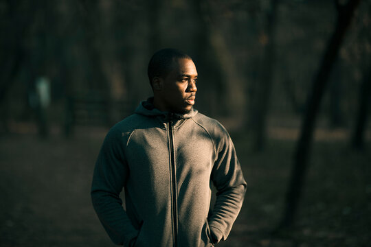 Man wearing hoodie standing in forest at dusk