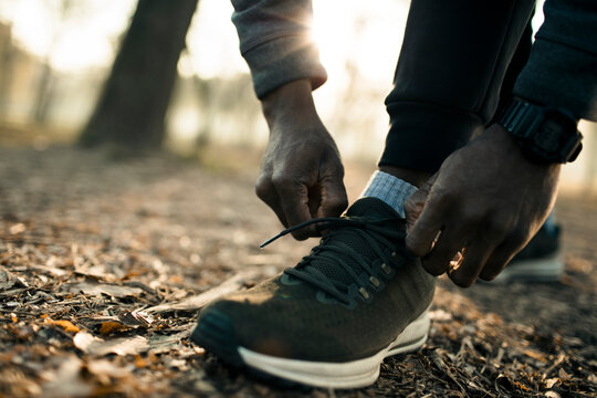 Runner tying shoelaces on forest trail at sunrise