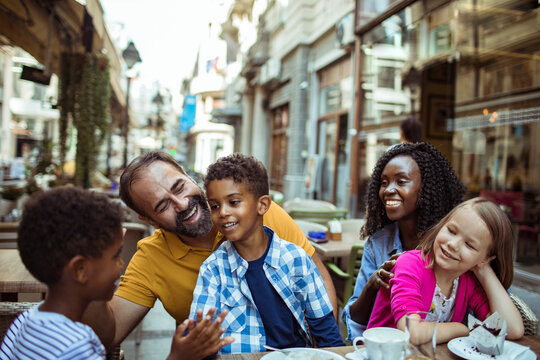 Happy family with children dining at outdoor cafe on a city street