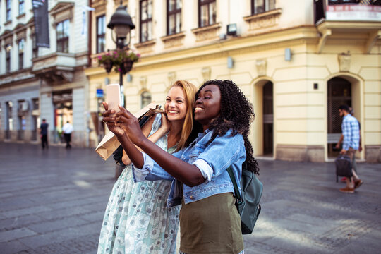 Two friends taking a selfie while shopping on a historic city street