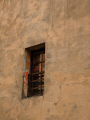 Obraz premium A window with bars, decorated with hearts, on an old wall.