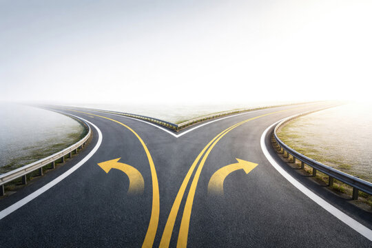 A fork in two roads with yellow arrows on the asphalt. Space for text.