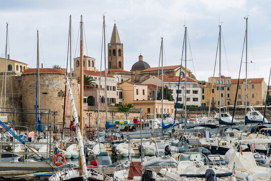 The port and the characteristic historic center of Alghero, Sardinia, Italy. Scenic coastal city featuring marina, waterfront, and well-preserved old town with Mediterranean architecture