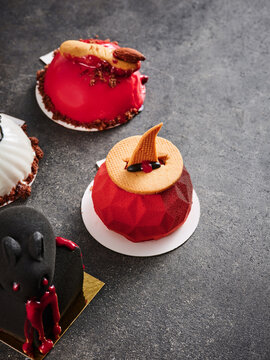 The image shows a variety of creatively decorated desserts, featuring bright colors and intricate designs. These treats are ideal for events, menus, and promotional materials in bakeries and caf&eacute;s