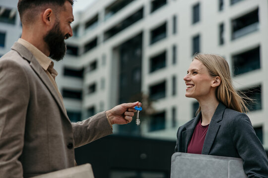 Real estate agent handing over keys to happy woman