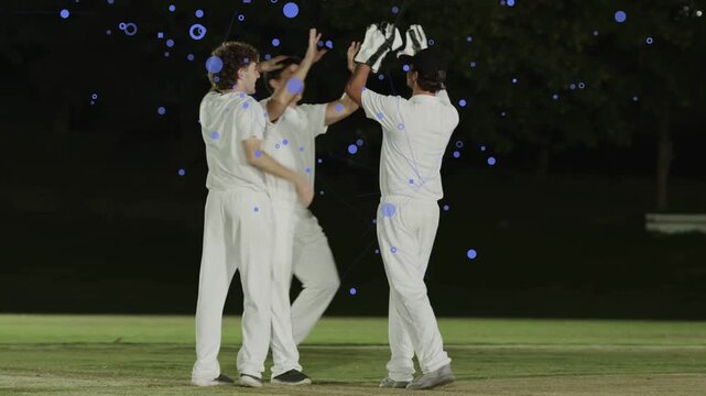 One player raising others running cheering wicket hugging patting gloved keeper blue dots floating