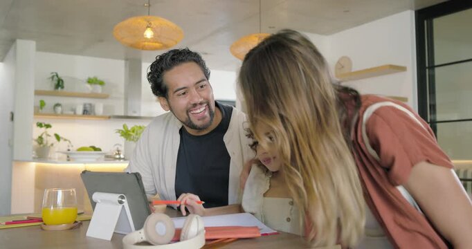Diverse family guiding child at kitchen island, mother entering, leaning and pointing at tablet