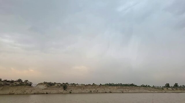 Lightning bolt striking the horizon over a river bank in a desert landscape during an overcast storm 240fps slow motion footage