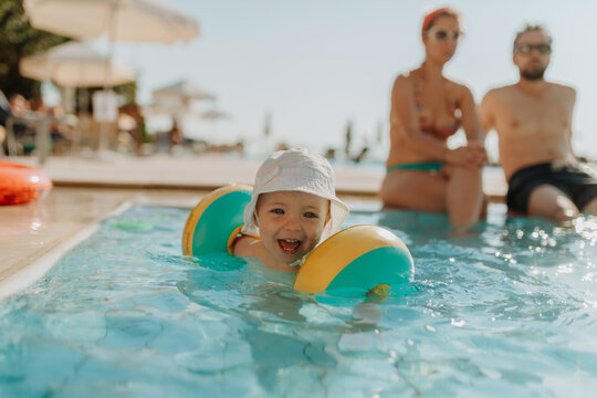 Happy toddler playing in pool during summer vacation.