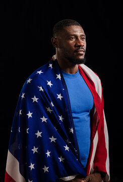 African American man standing in studio, holding American flag and wearing blue crewneck shirt
