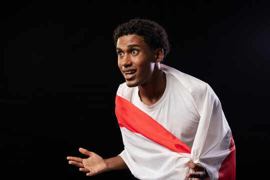 Man leaning forward and gesturing, holding red-and-white cloth over white T-shirt in studio