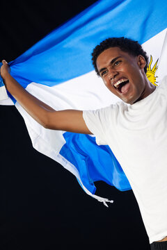 African American man waving blue-and-white flag with golden sun, wearing white t-shirt in studio