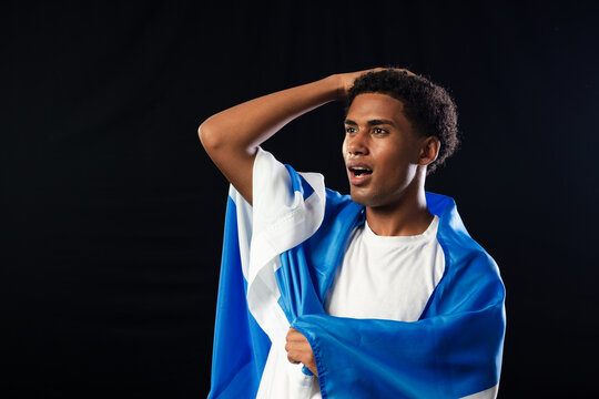 African man standing right in studio holding blue white cloth wearing white tee, copy space