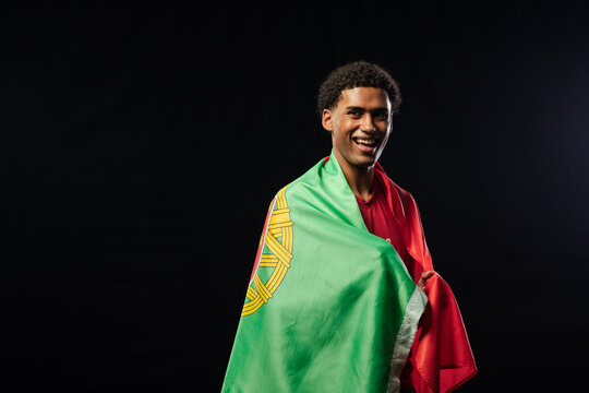 Man smiling draped in green red flag with yellow emblem red-shirted in studio lighting, copy space