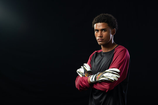 African American male keeper posing in studio crossing arms, wearing jersey and gloves, copy space