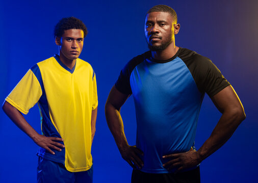 African American men posing in studio, wearing blue and yellow jerseys and bracelet