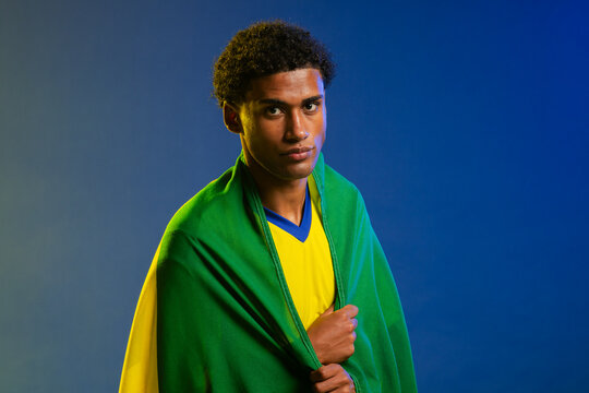 African American man in mid-20s posing in studio wearing blue-trimmed yellow jersey and green flag