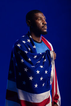 Mid adult man looking up while wearing American flag and blue crewneck shirt in portrait studio