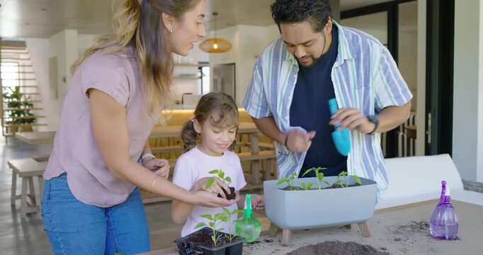 Family of three planting seedlings at kitchen patio planter, child holding seedling starting lesson