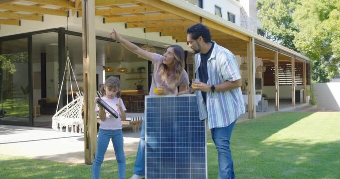 Family parents guiding, pointing, daughter raising small panel in yard for mounting by large panel