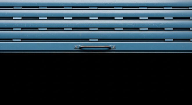 Close-up of a closed blue metal security roller shutter with a horizontal handle, abstract