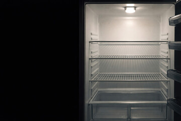 Fototapeta premium An empty open refrigerator with lighting inside. Space for text.