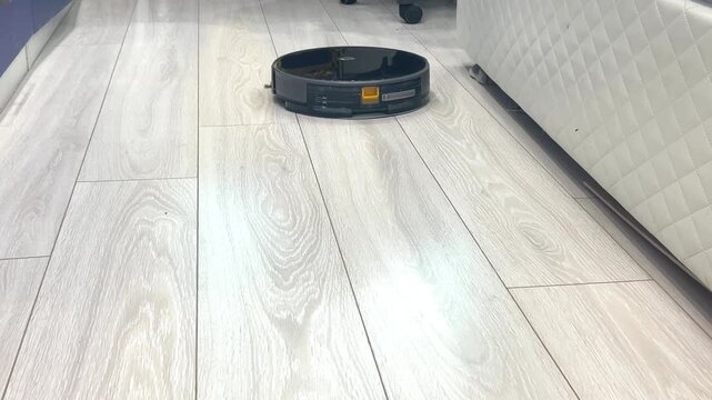 Robot vacuum cleans living room floor in a modern home during daytime hours