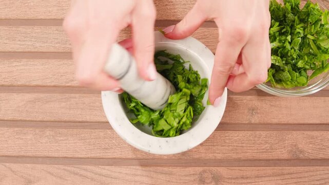 Glass bowl with chopped spinach and a board with onion and dill on a light blue background, top view. Cooking healthy vegan food