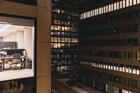 Beleuchtetes B&uuml;ro und Hochhausfassade bei Nacht in der Gro&szlig;stadt, urbane Architektur