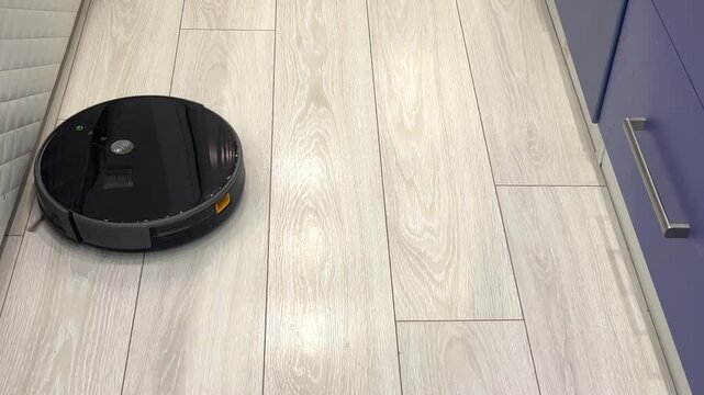 Robot vacuum cleans floor in a modern kitchen on a weekday morning