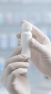 Gloved hands hold a small white bottle