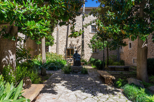 Mallorca, Spanien: Wanderung auf dem GR 221 zum Kloster Lluc, Santuari de Santa Maria de Lluc - Sehensw&uuml;rdigkeit f&uuml;r Touristen: das Geb&auml;ude mit Statue im Garten, Innenhof