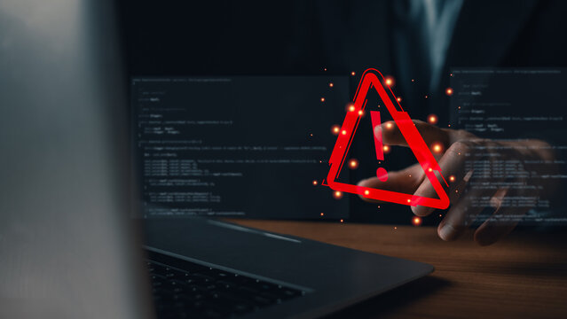 Programmer pointing at a red virtual warning triangle icon on a screen with coding background. Concept of cyber attack, system error, data breach, software bug, and internet security alert.