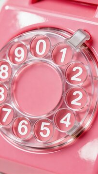A pink rotary phone dial with clear and pink buttons, showcasing a nostalgic and retro design, perfect for representing vintage technology and communication.