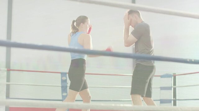 Female boxer and male exchanging red-gloved jabs in boxing ring male initiating feints for training
