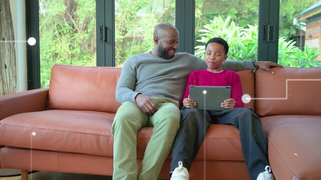 Dad leaning and gesturing, son tapping tablet, activating animated white-dot links for education