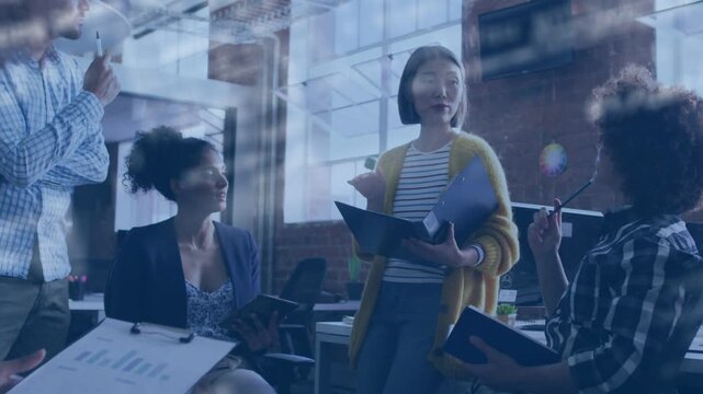 Standing presenter opening blue binder and briefing team in office, moving overlay obscuring hands