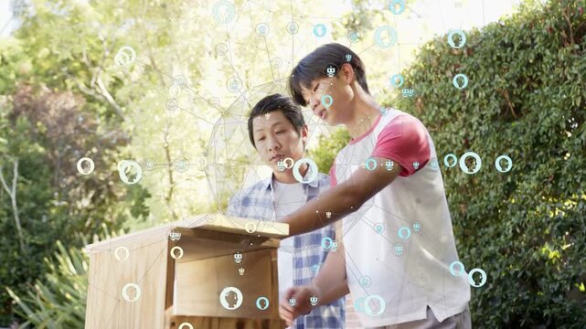 Vertical video: Holding wooden box father guiding teen lowering plank fitting lid at yard table HUD