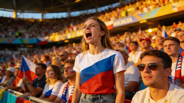 Cheering female fan wearing blue-white-red t-shirt and denim at railing, waving Czech flags