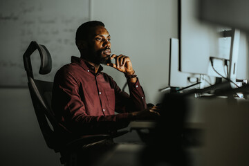 Focused professional working late at computer in a dimly lit office space © BGStock72