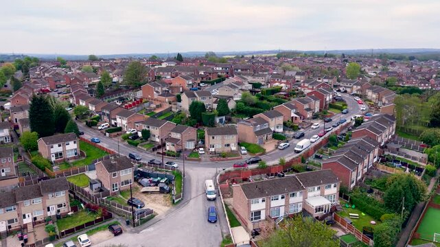Aerial drone footage above a generic suburban housing estate in England with tight knit community and houses crowded together.