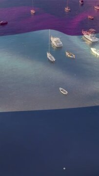 Vertical video: Rising tide driving dark band sliding over moored boats and rippling teal water